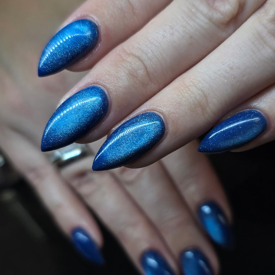 Close-up of hands with blue stiletto nails on a dark background