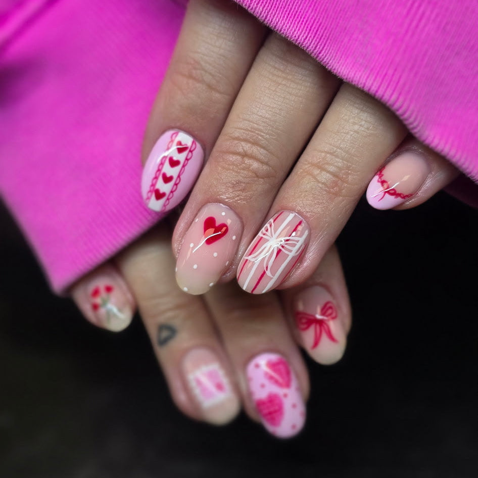 Close-up of hands with colorful nail art against a pink background