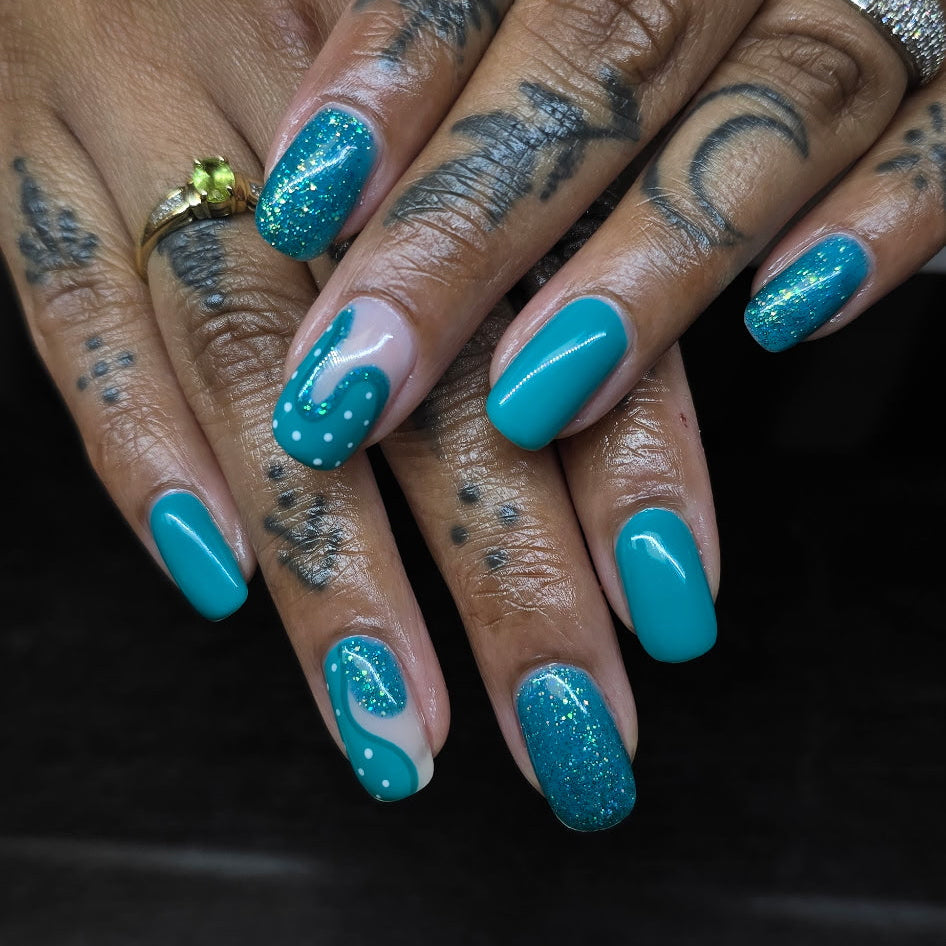 Close-up of hands with teal nail polish and tattoos on a dark background