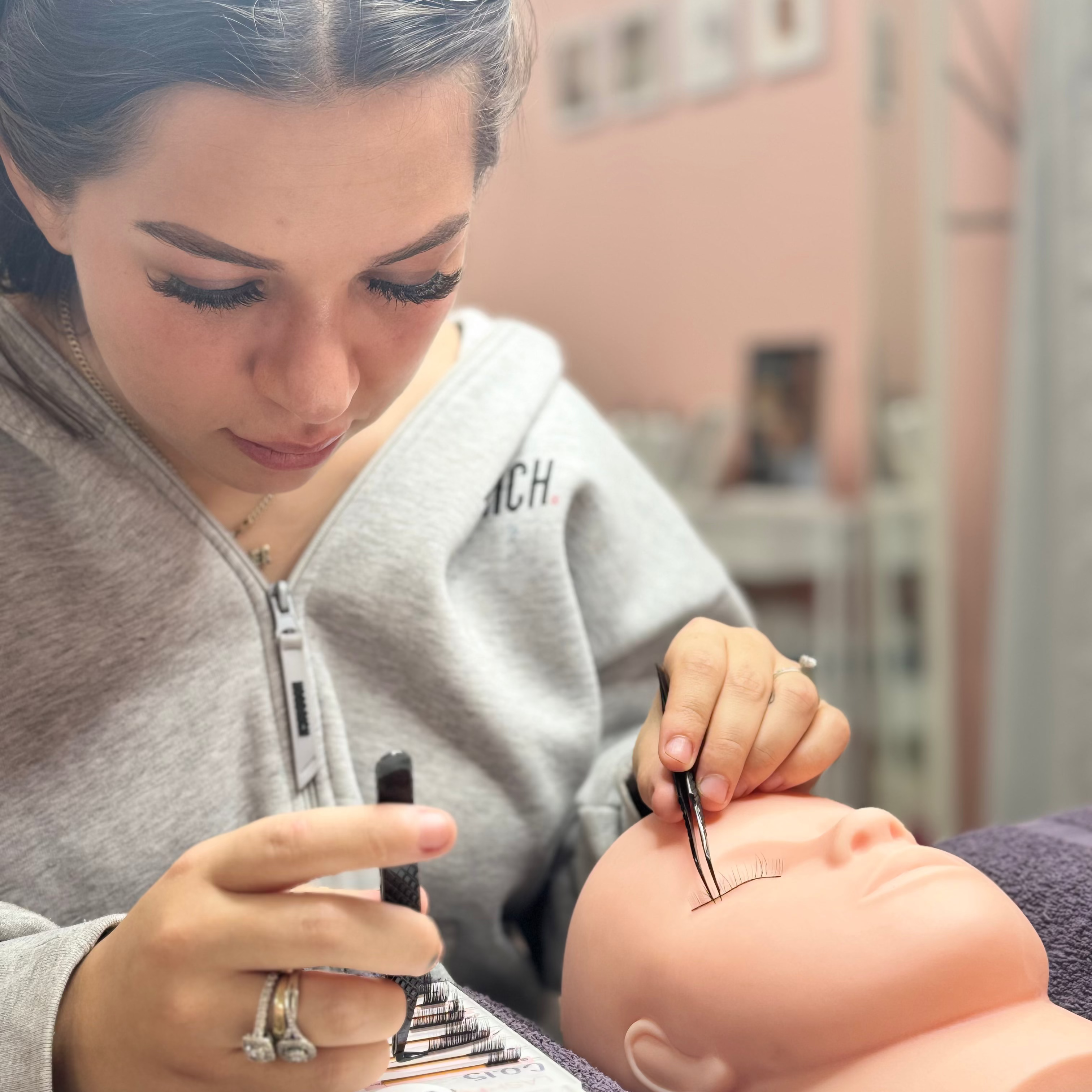 Person practicing eyelash extensions on a mannequin head.